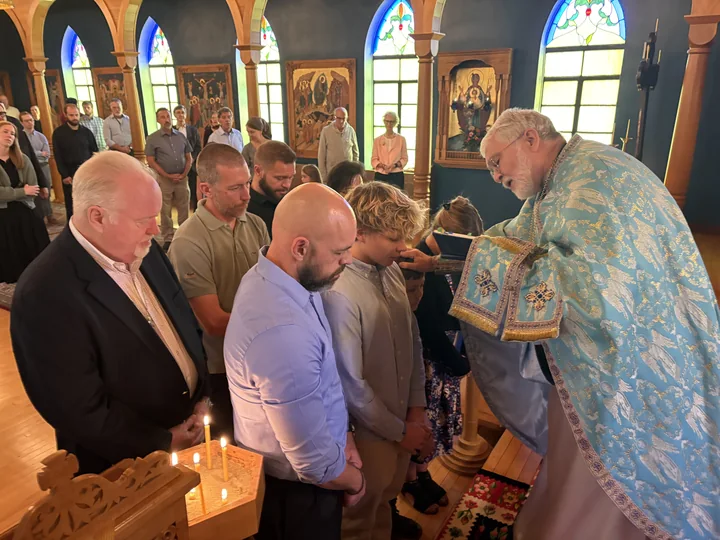 A priest praying with a group standing before him in the church