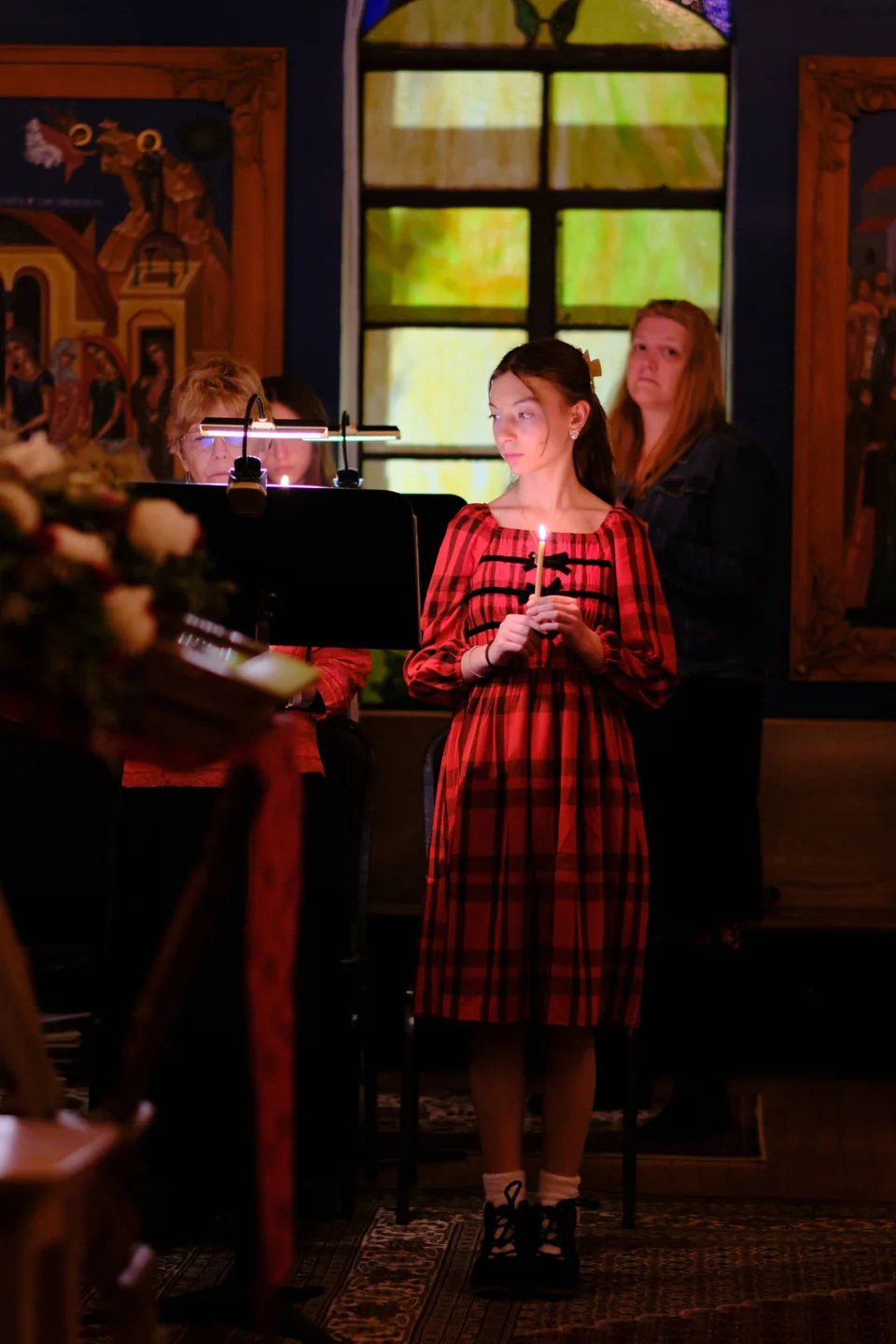 A young parishioner holding a candle beside the choir