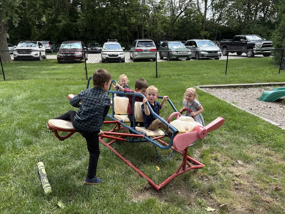 Children playing together on an airplane-shaped playground ride outside the church